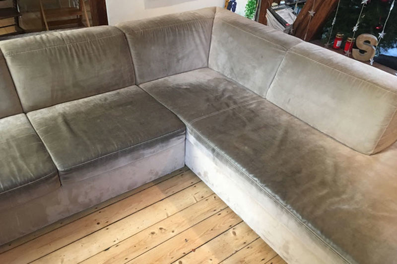 Ecksofa mit vergrautem, fleckigem Veloursbezug vor der Reinigung